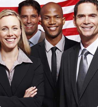 Four professionally dressed people in front of American flag. 