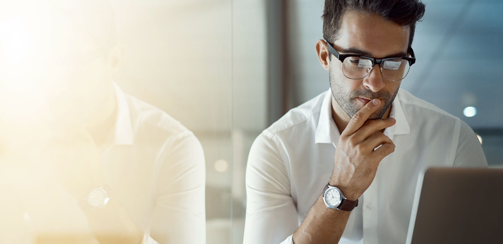 Man with glasses looking at a computer