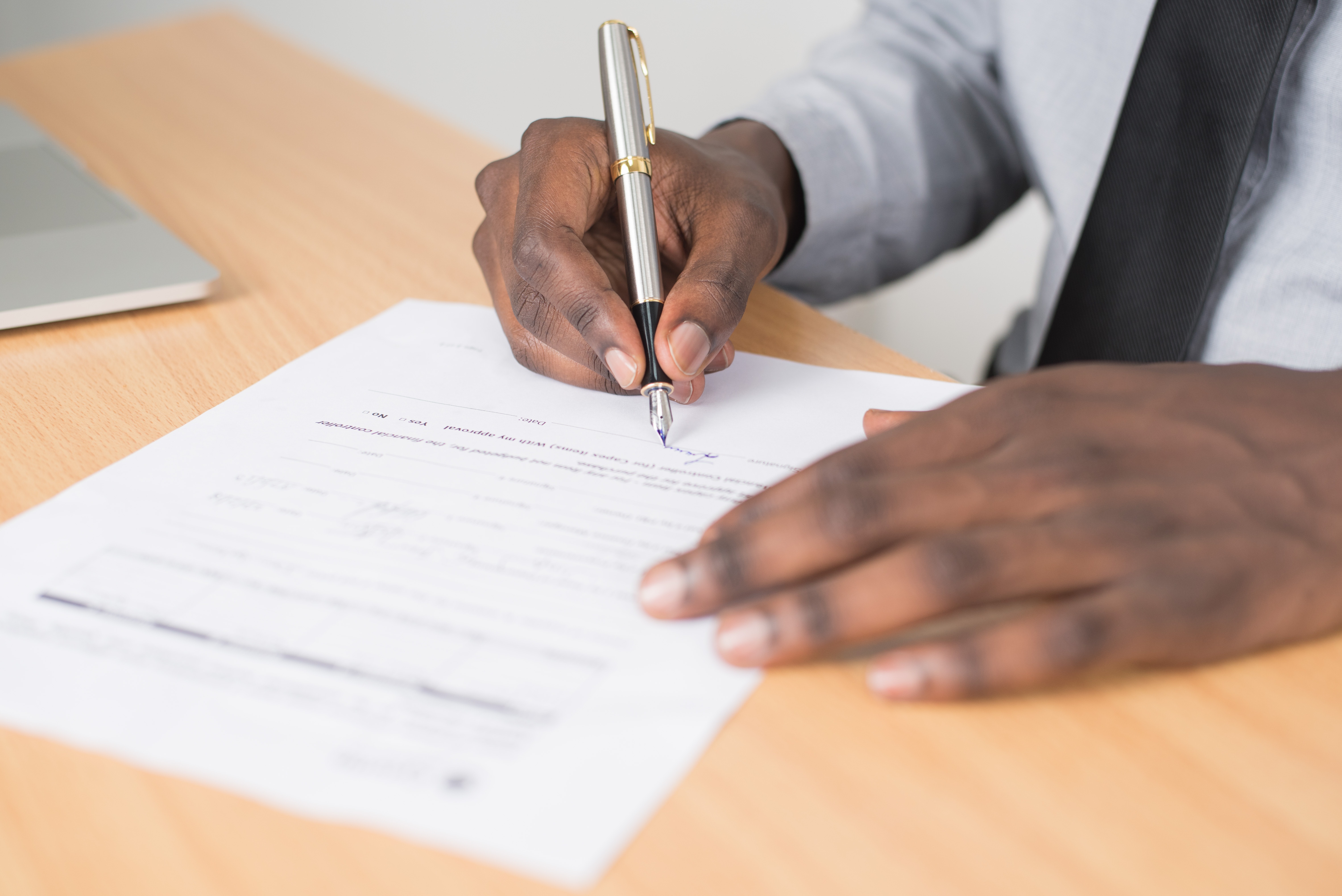 Hands holding a pen and writing on paper.